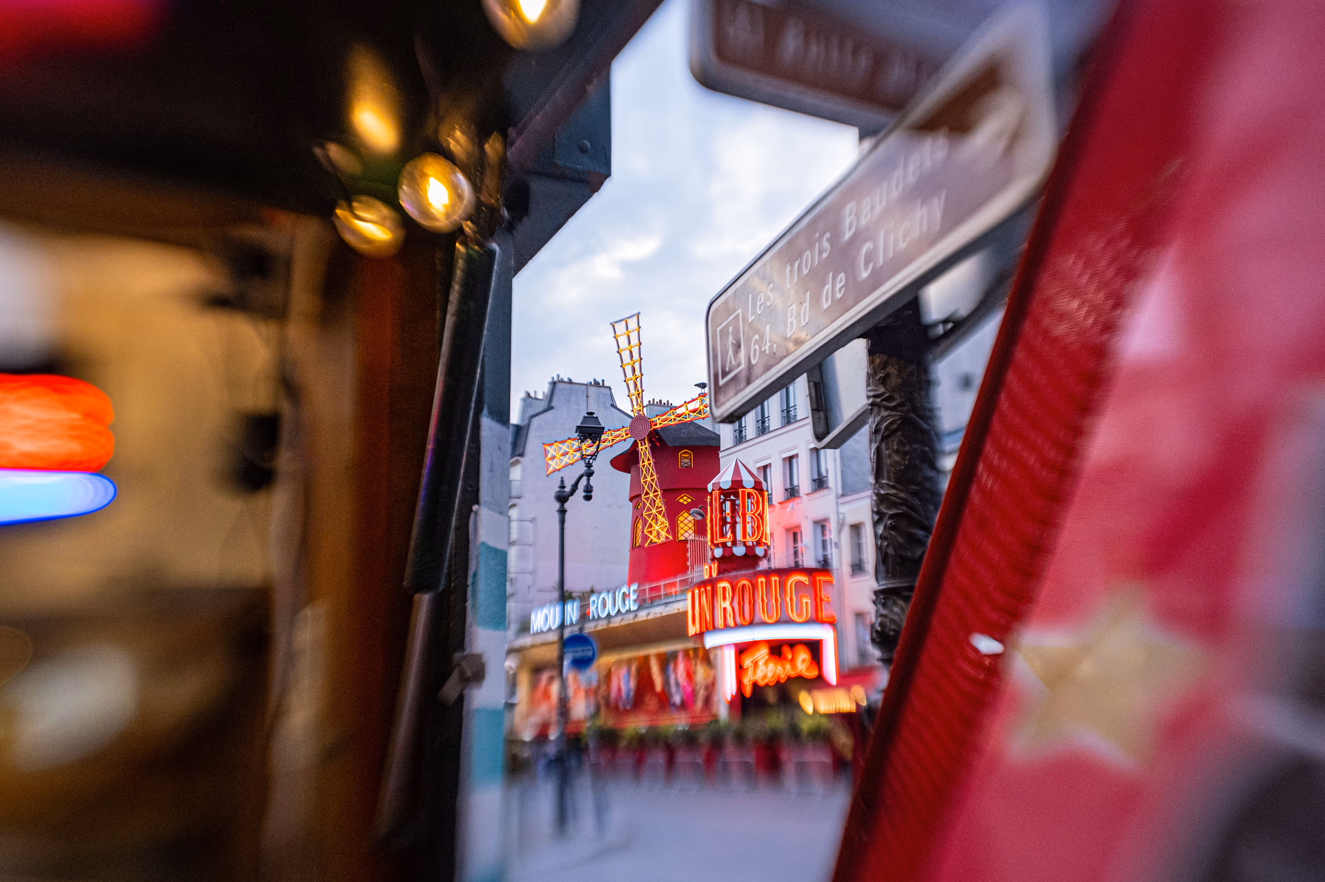 Blick auf das Moulin Rouge in Paris zwischen unscharfen roten Elementen im Vordergrund
