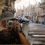 Fotograf mit Rangefinder-Kamera in Pariser Straße, Test Fujifilm X100V, X-E4 und Nikon Zfc