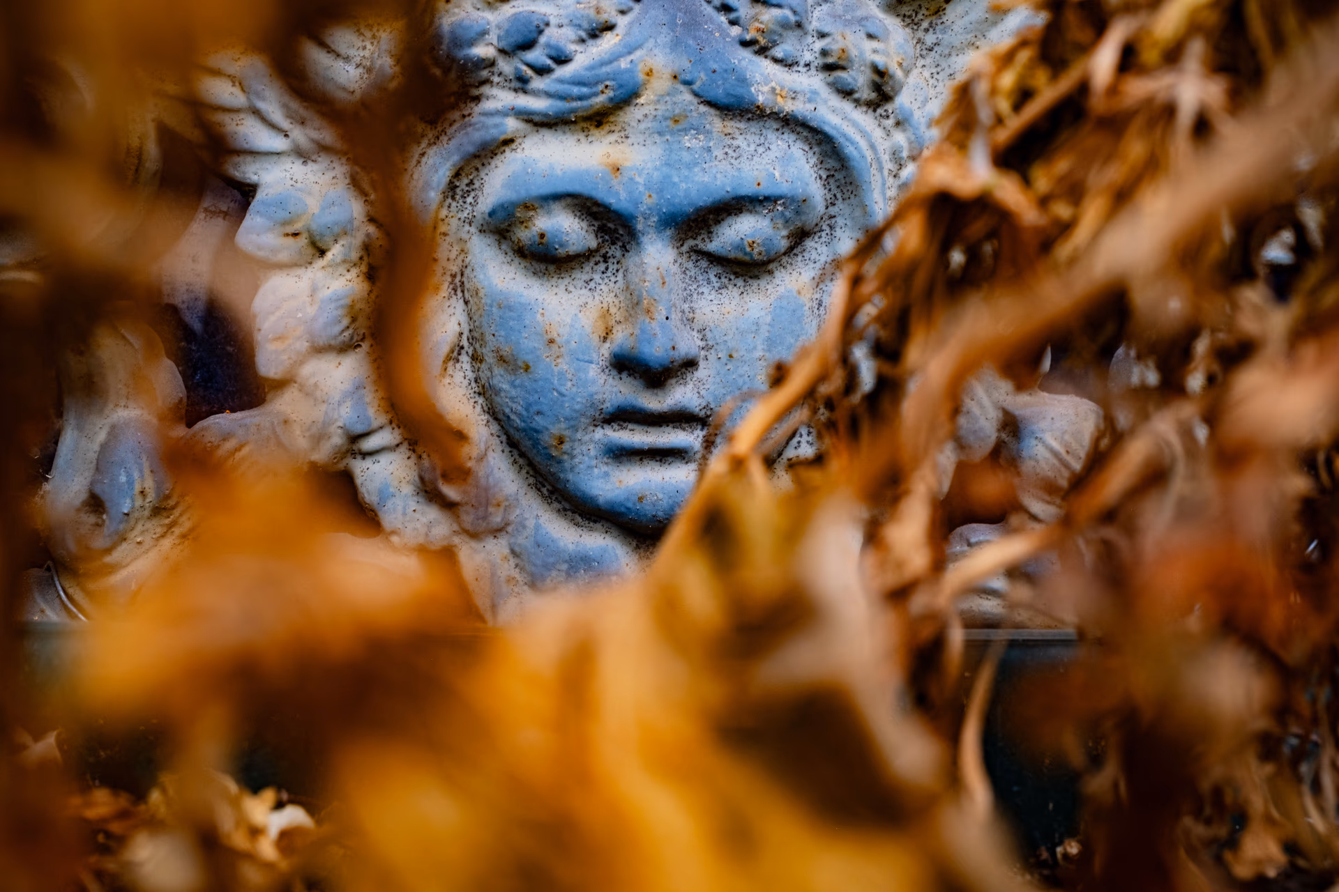 Nahaufnahme einer blauen Steinskulptur mit unscharfem goldenem Dekor im Vordergrund