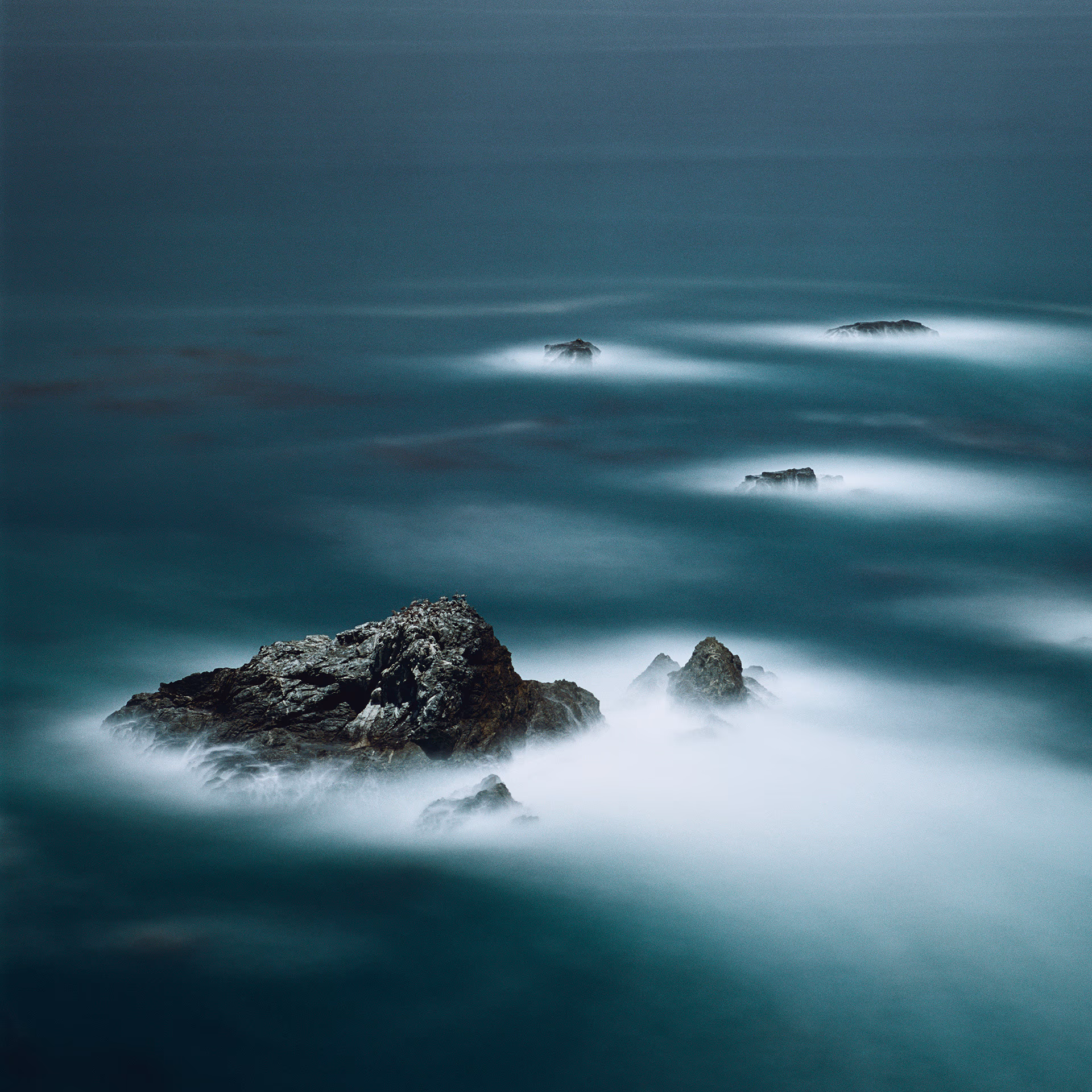 Felsformationen im Meer bei Nacht, umhüllt von Gischt