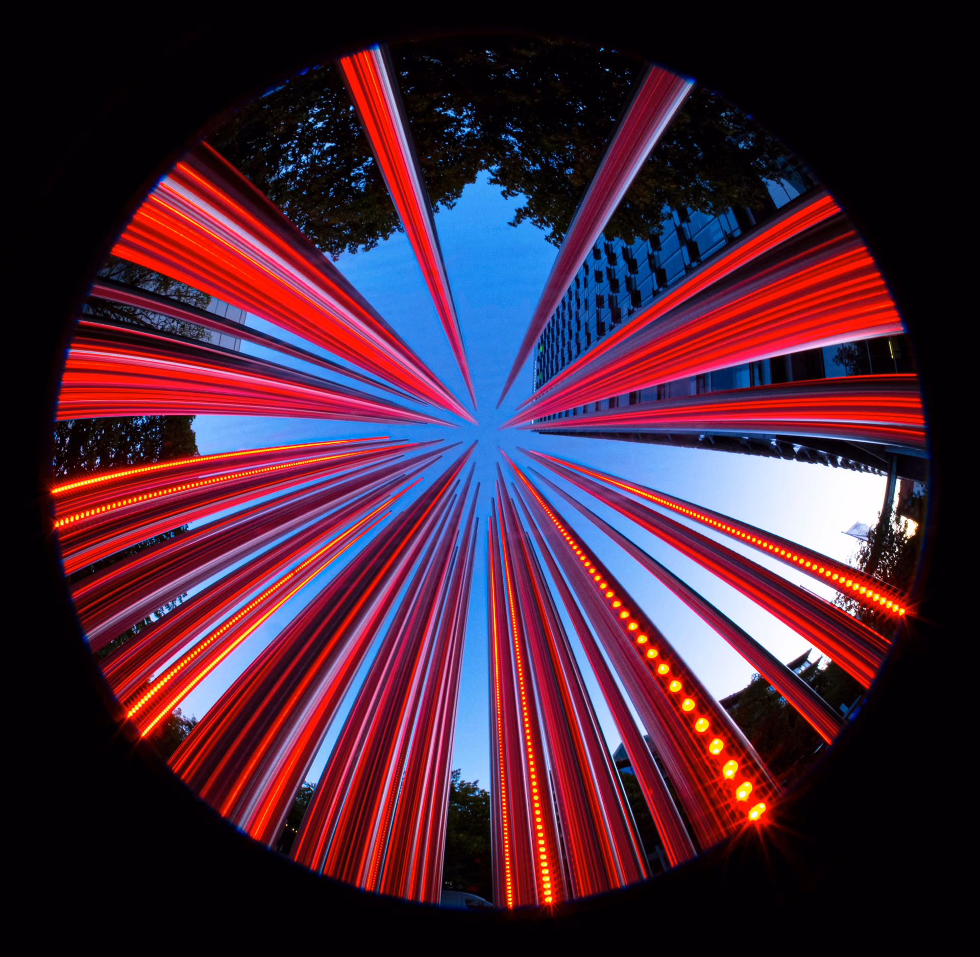 Lichtspuren von roten Lichtern, die sich zu einem Stern am blauen Himmel formen.