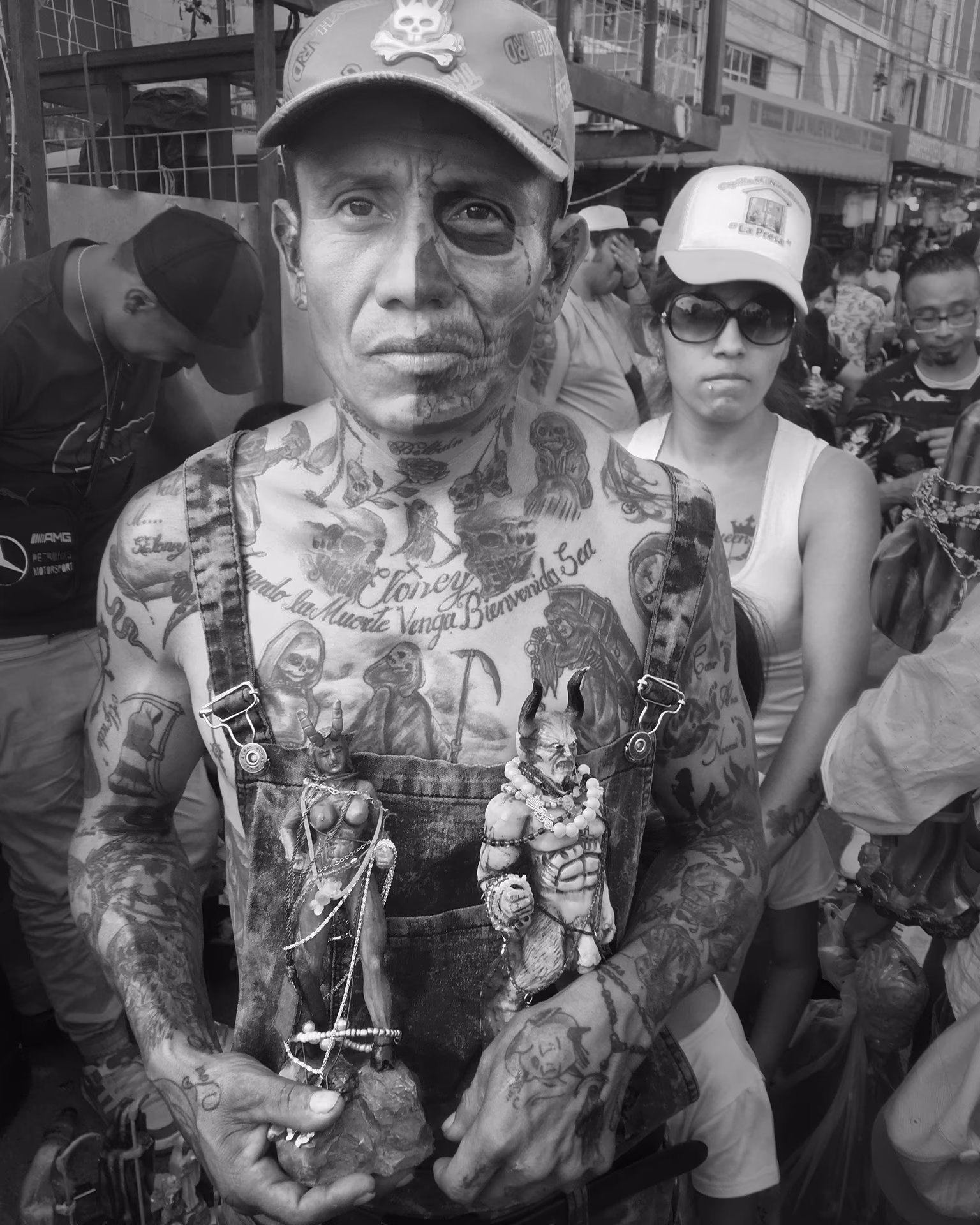 Mann mit Gesichtsbemalung und Tattoos hält Figuren in den Händen