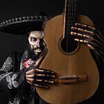 Mann mit Totenkopf-Make-up und Sombrero hält eine Gitarre, inspiriert von Catrinas am Kanal.
